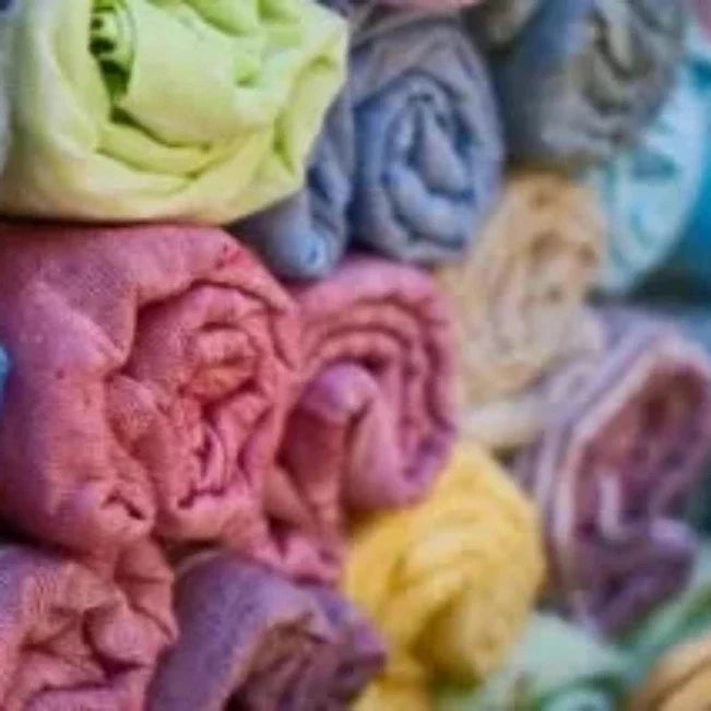 Opgerolde handdoeken opgestapeld in roze, paars, blauw, groen en geel.
