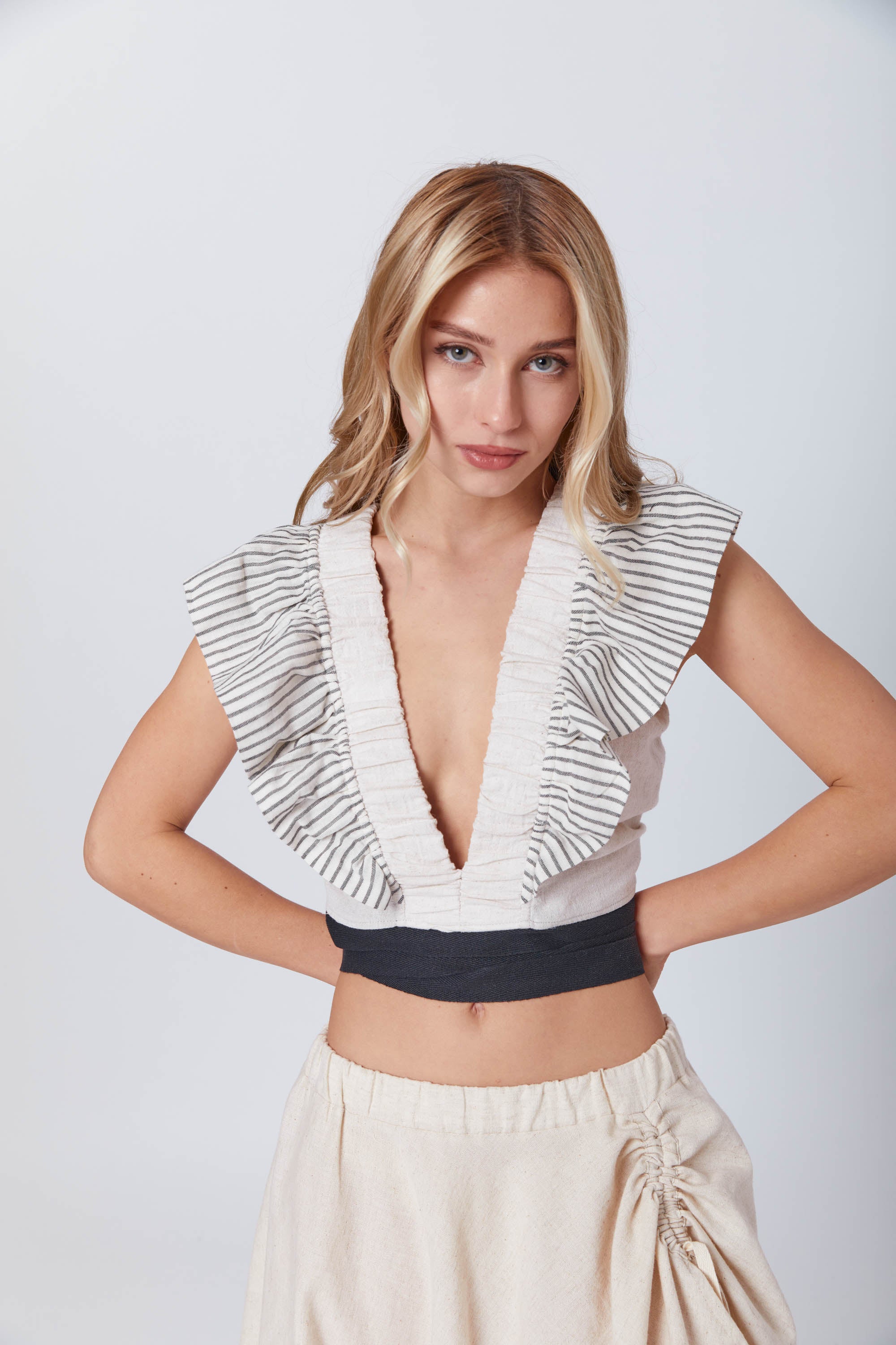 Blonde woman model posing in a ruffled V-neck top and light skirt