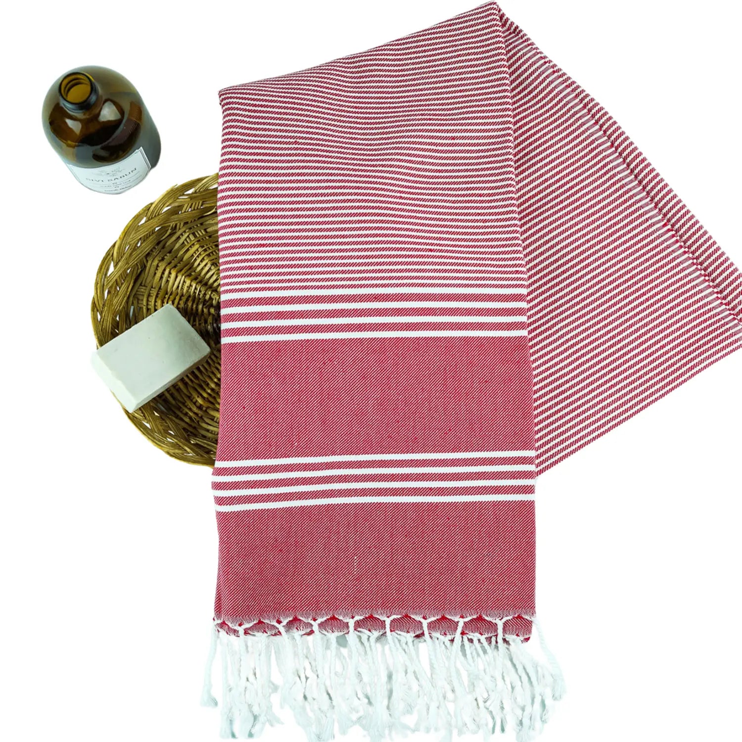 Red and white striped Turkish cotton pestemal towel with handmade tassels, styled with a soap bar and oil bottle.
