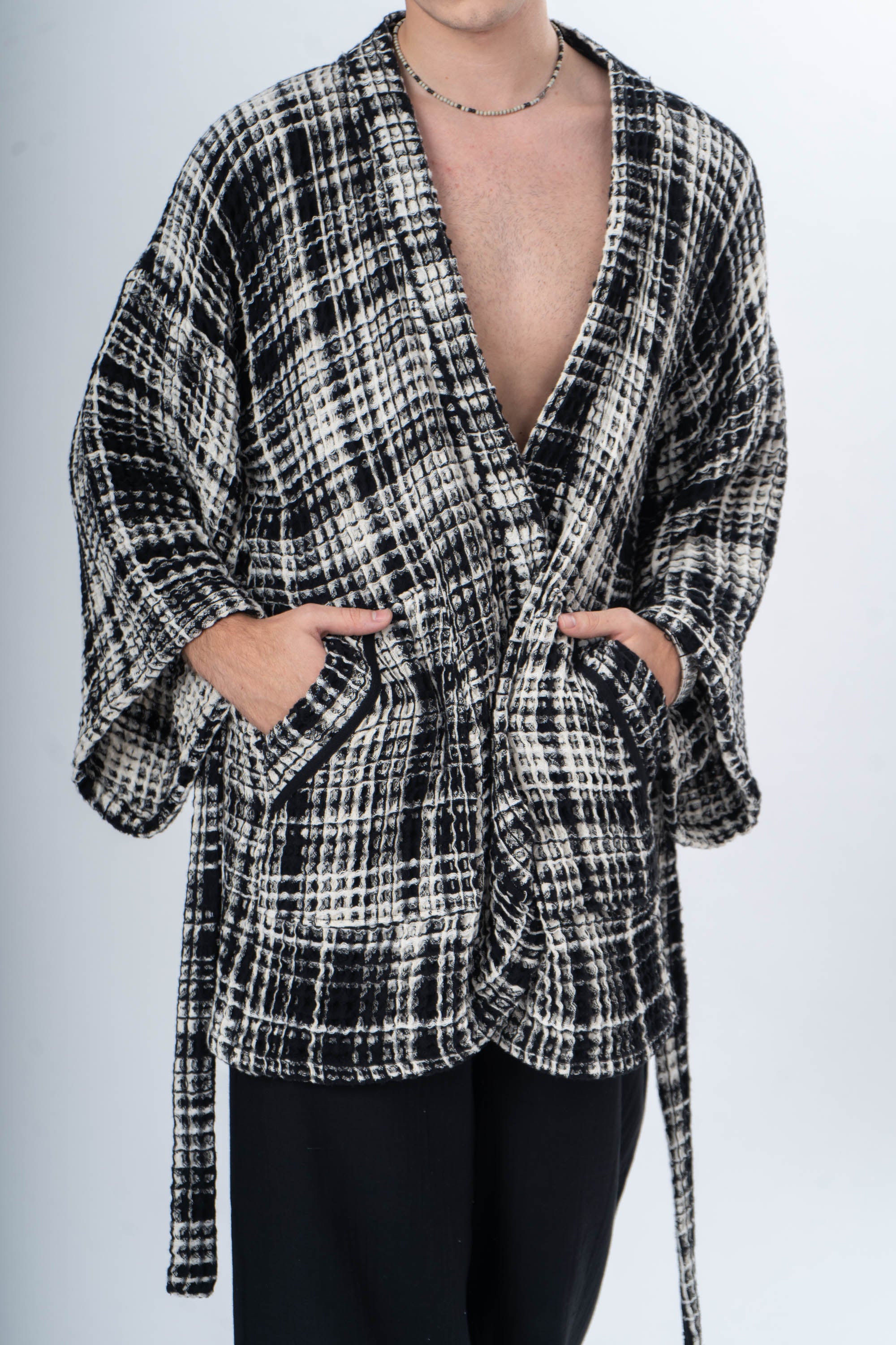 A man wearing a black and white plaid Trimita kimono robe against a plain background.