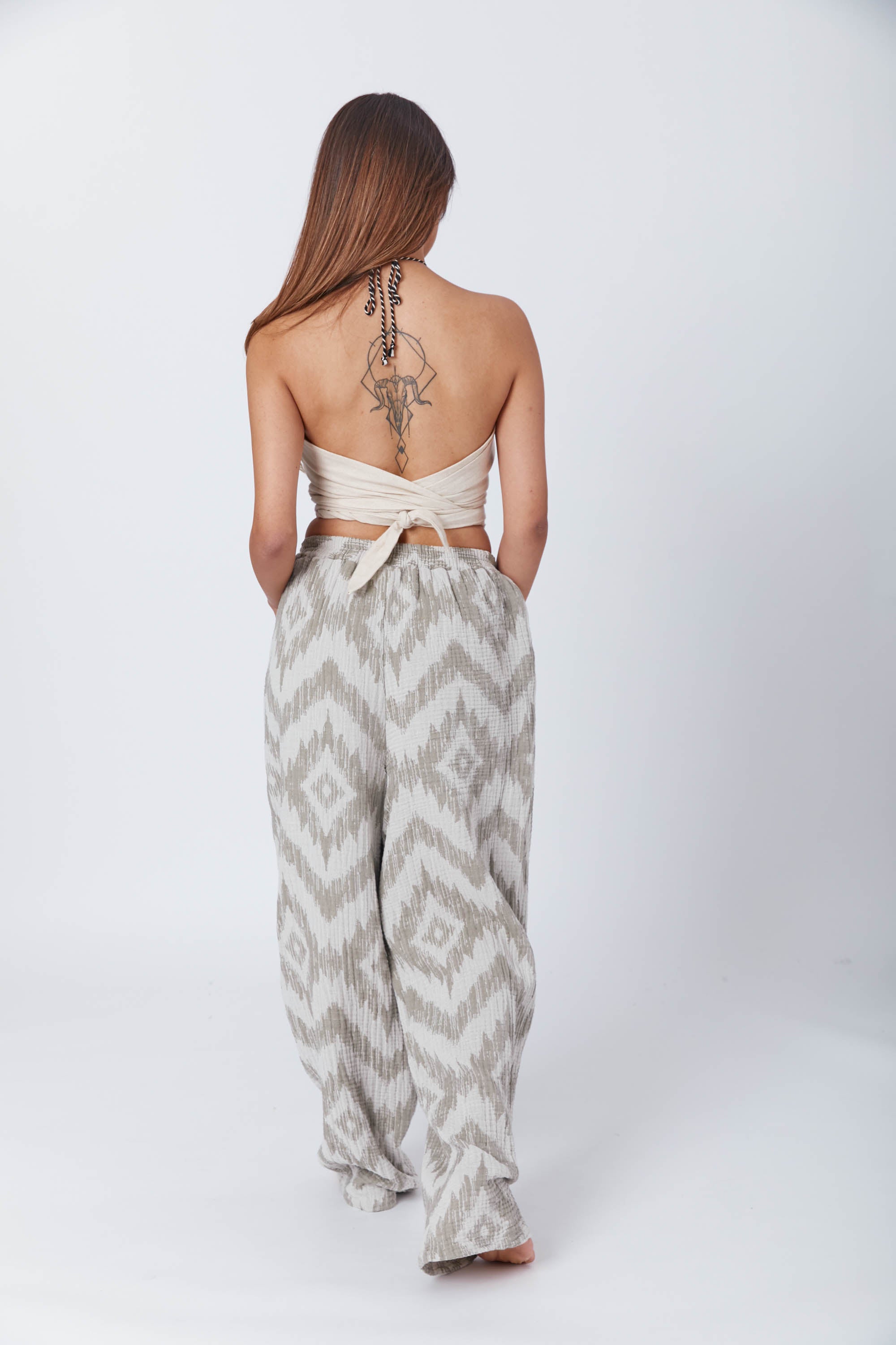 Confident woman barefoot in a cozy matching patterned set and cream wrap top, giving off laid-back boho vibes