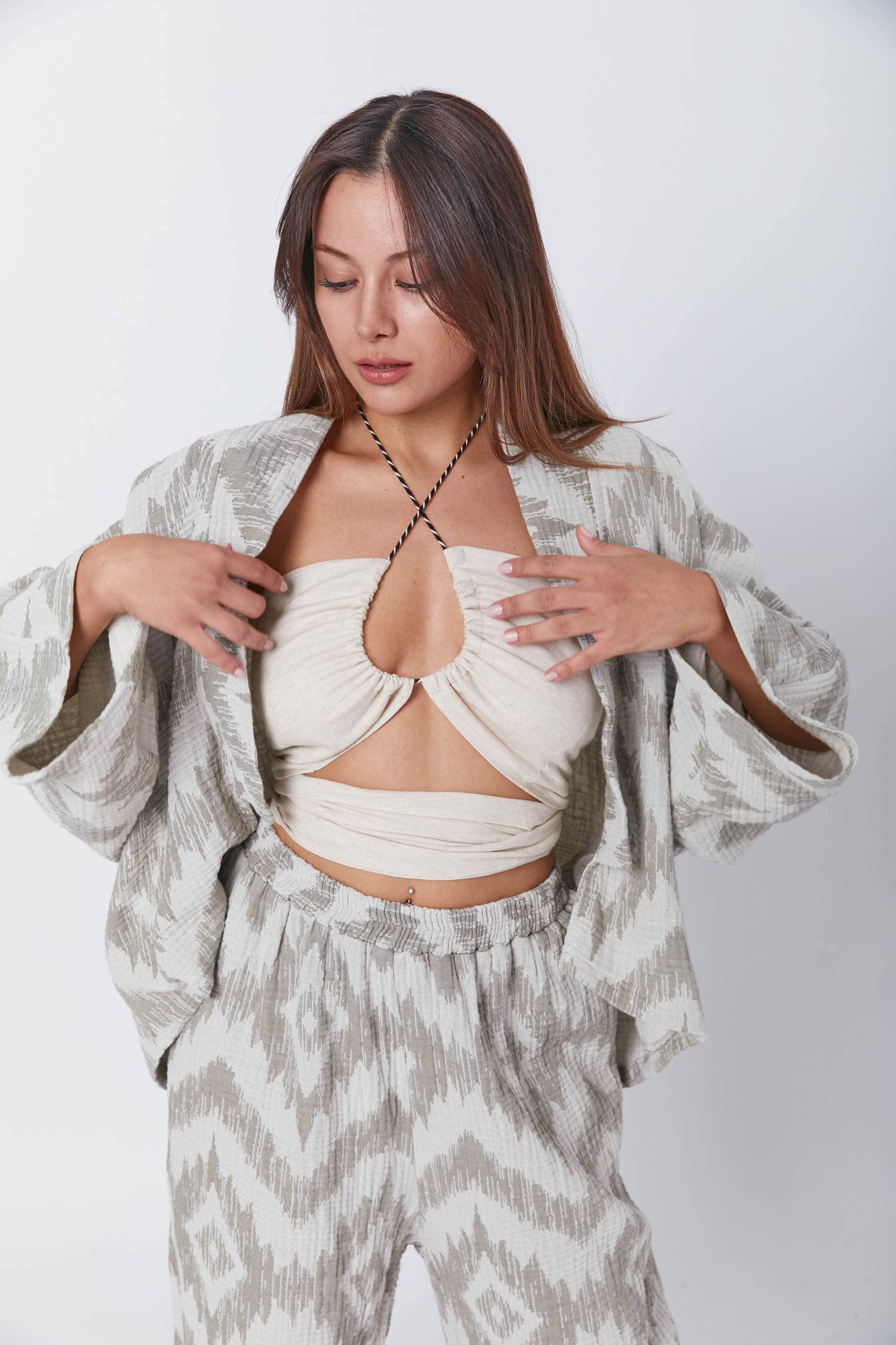 A woman wearing a soft-textured joint suit consisting of wide-leg trousers and a Guru Green muslin jacket with an open front.