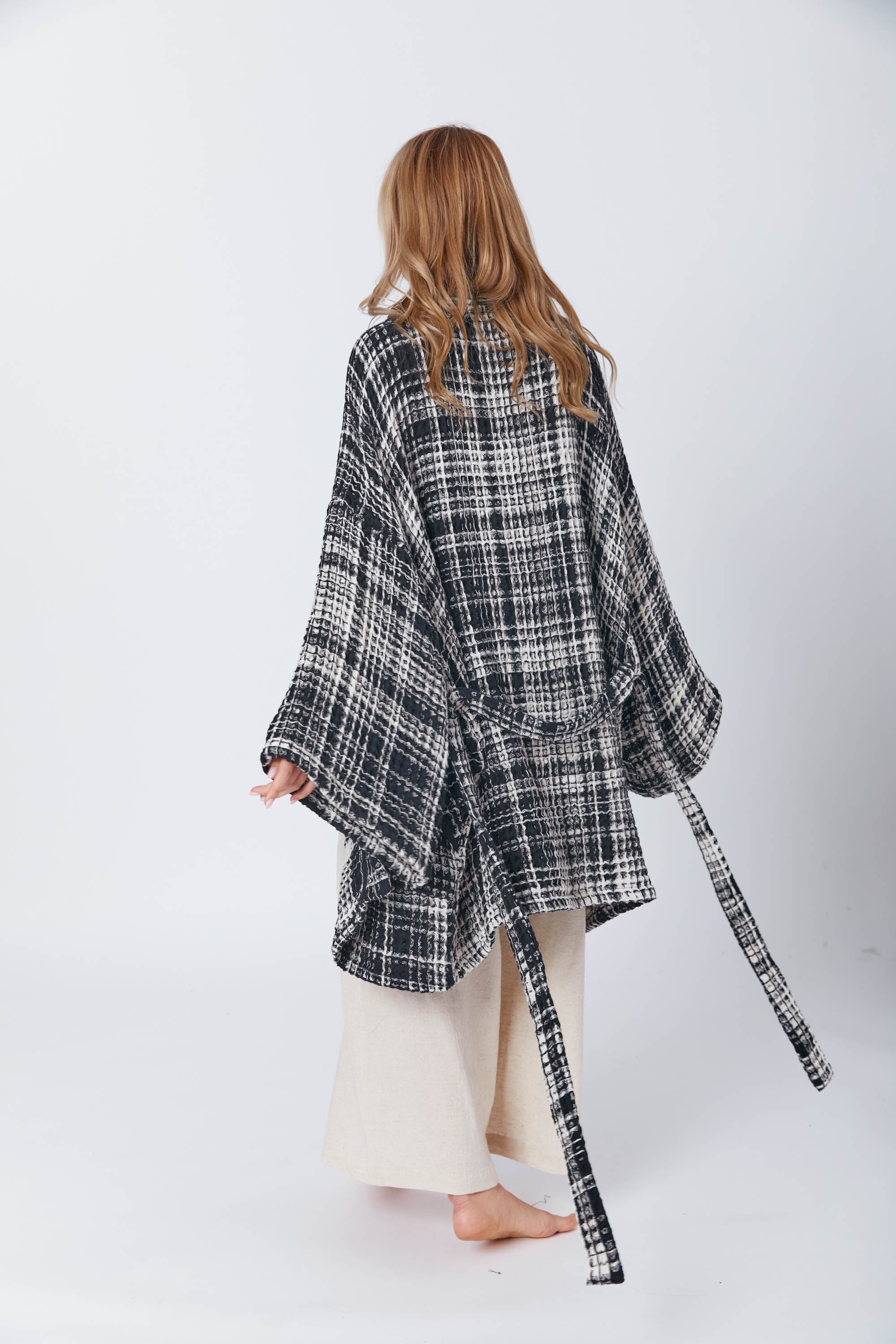 Model wearing a cream wrap crop top and flowy beige pants, styled with an oversized Trimita Prana black kimono cardigan in motion