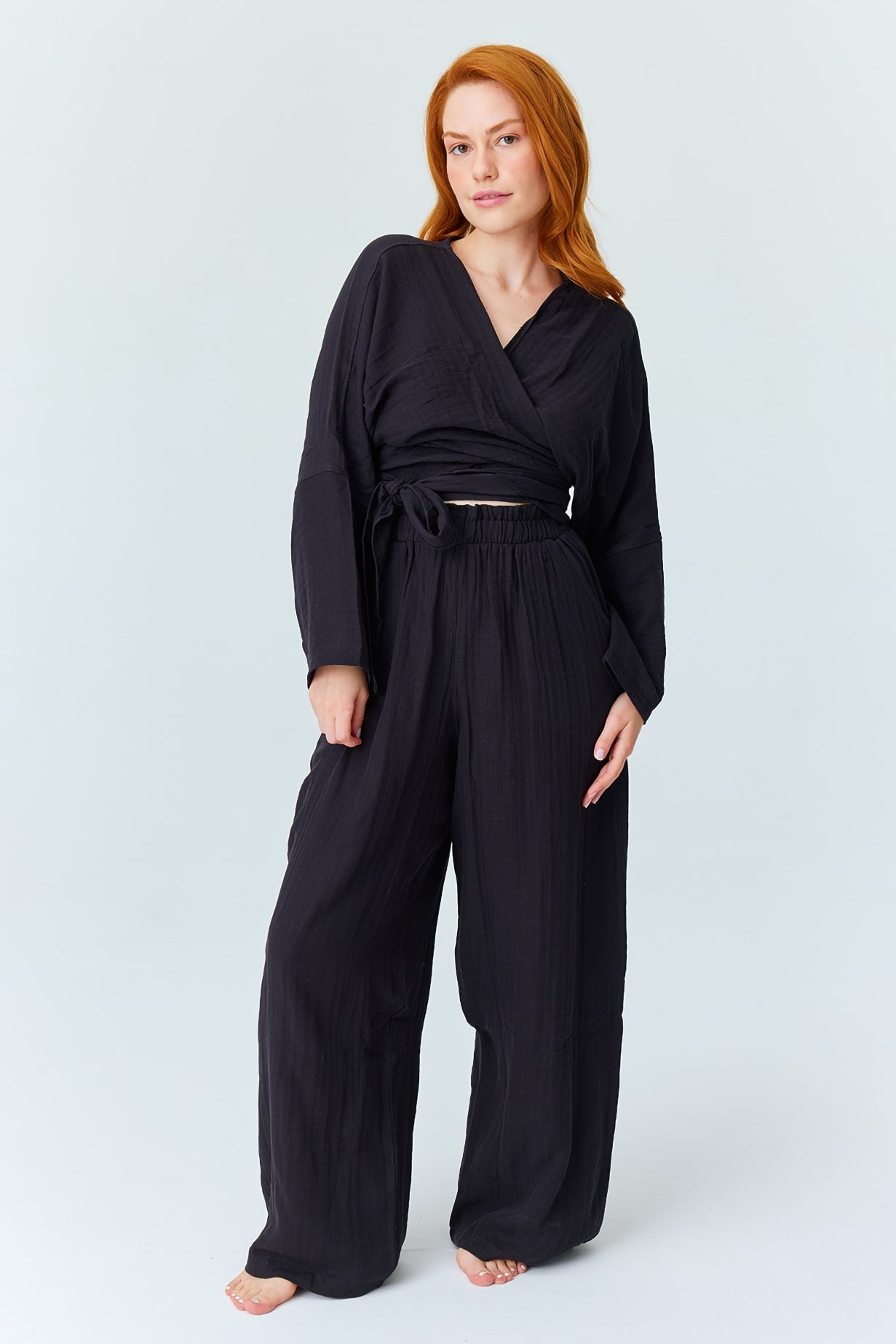 Woman in black loungewear set posing against light background- Trimita