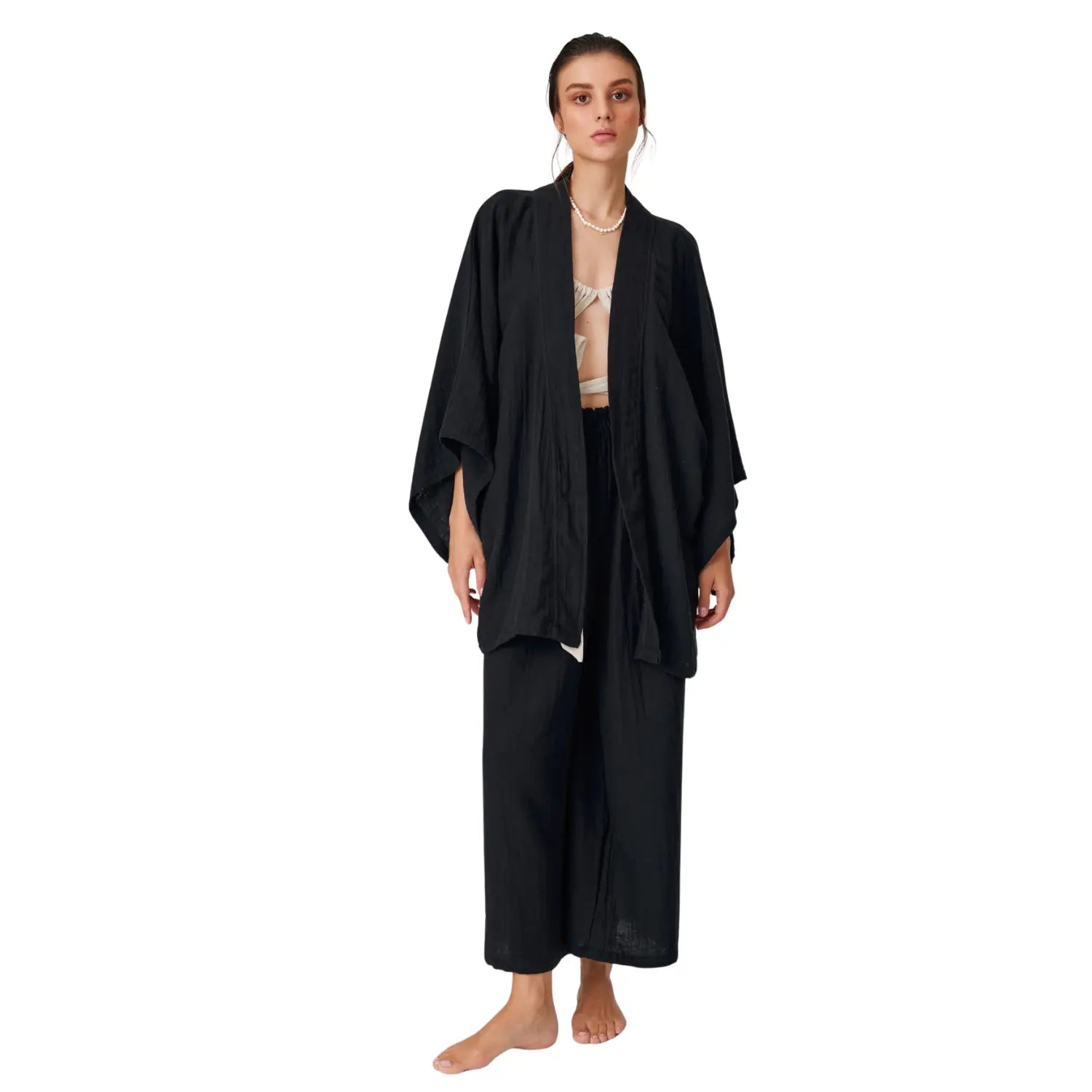 Front view of a woman wearing a modern, bohemian style black cotton muslin kimono robe with large pockets.