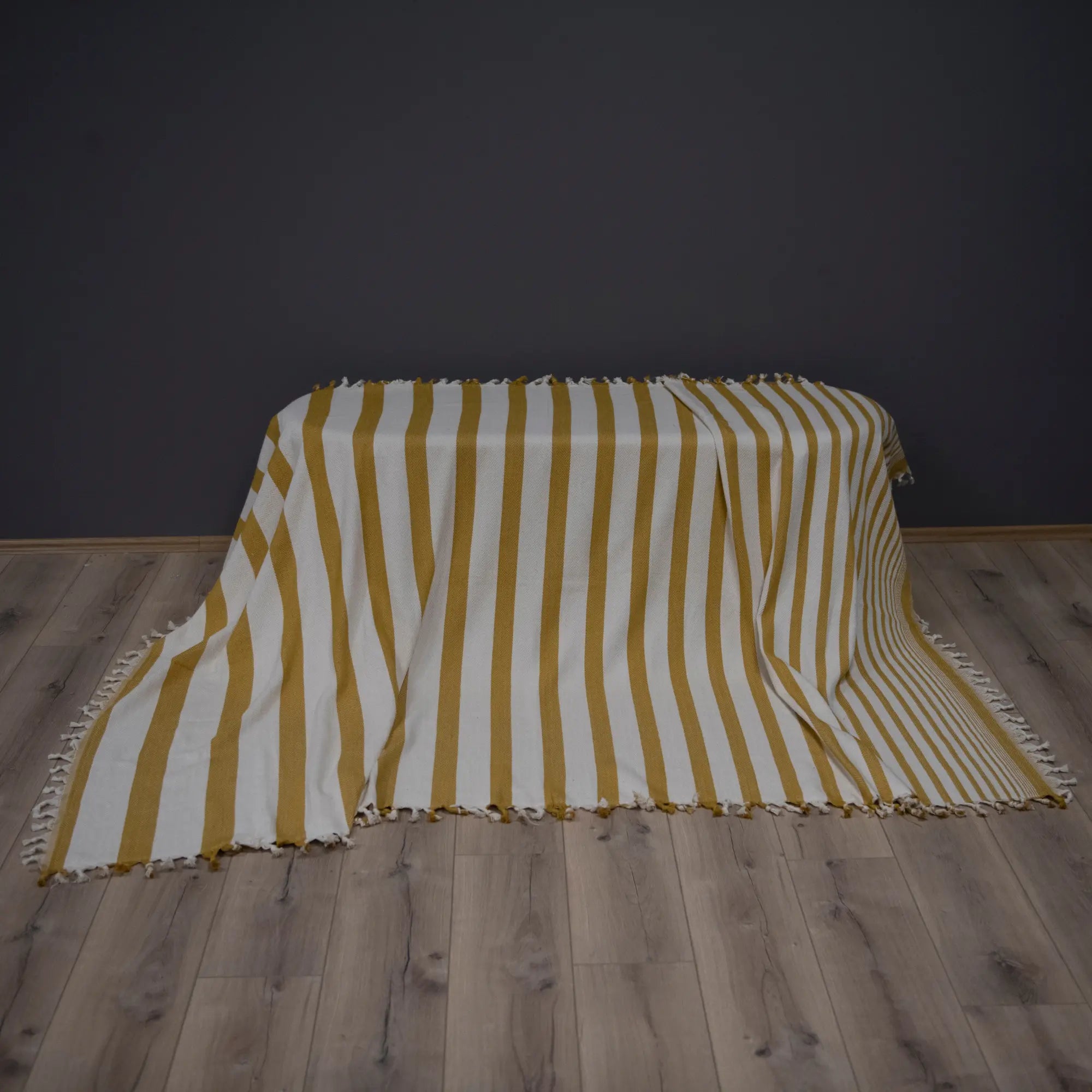 Trimita Sevda Bedspread in mustard stripes, folded on a sofa