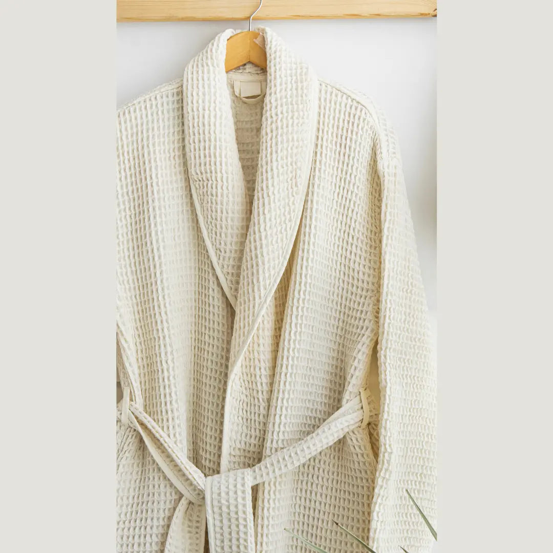 Beige waffle-textured Trimita robe hanging on a wooden hanger against a white background