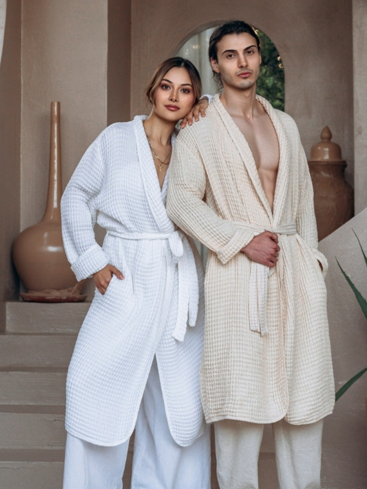 Two people wearing white and beige Turlkish Cotton Trimita Soft Waffle robes standing close together indoors.