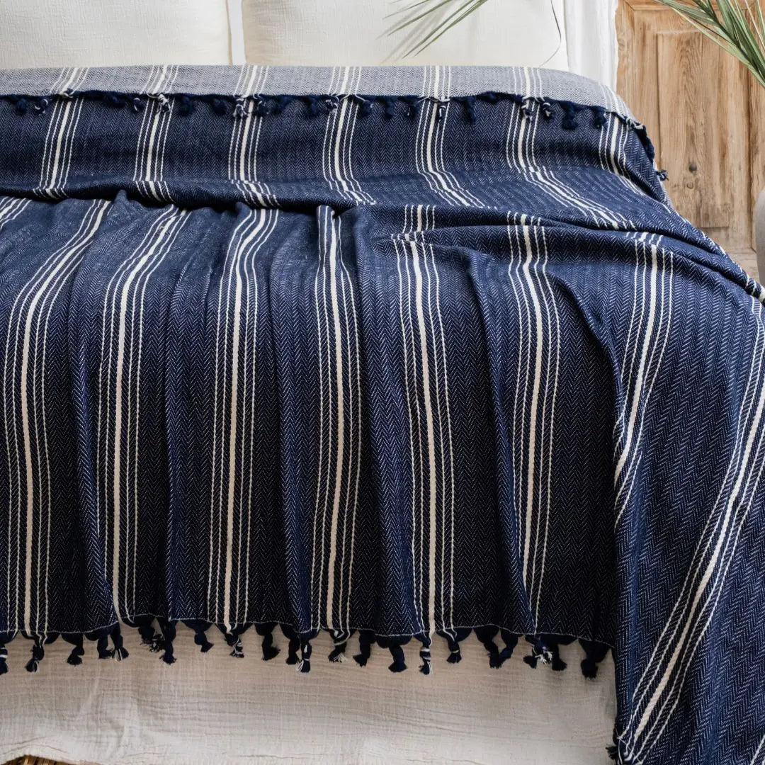 Yasmin Couvre-lit par Trimita – couvre-lit en coton bleu marine à rayures blanches avec pampilles, présenté sur un lit en chambre