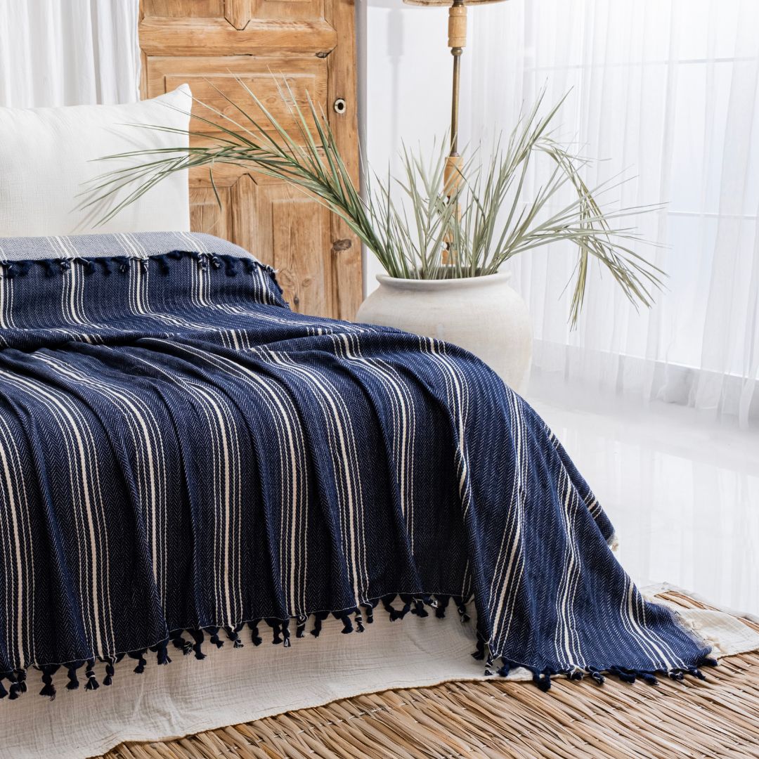 Yasmin Bedspread by Trimita – oversized king size cotton bedspread in navy with tassels, styled on a bed in a bright bedroom setting