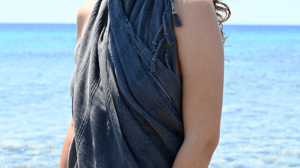 A girl holding coral Turkish Hammam Towel at the beach-sea-summer | Trimita