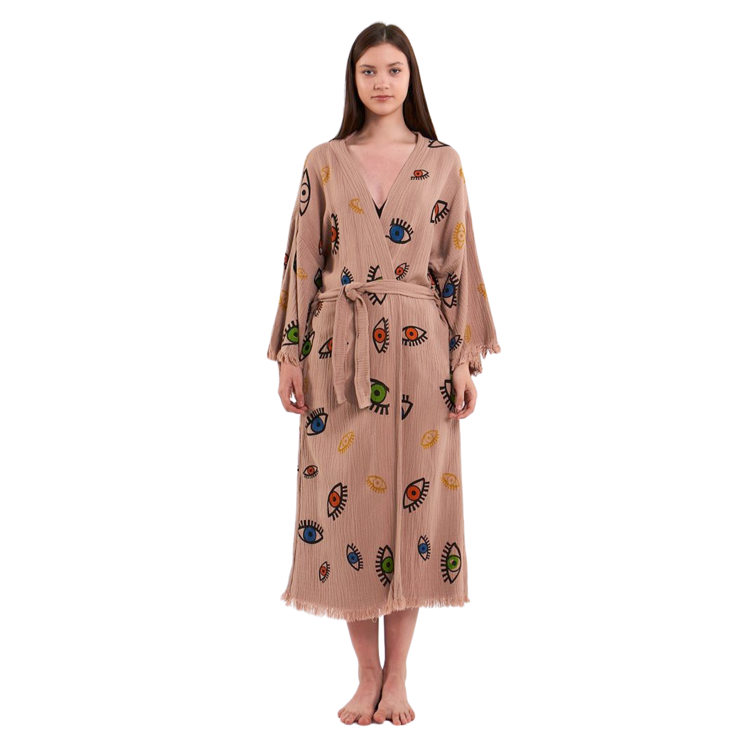 Full-body shot of a model wearing a beige kimono robe with a colorful eye pattern, standing with arms relaxed by her sides.