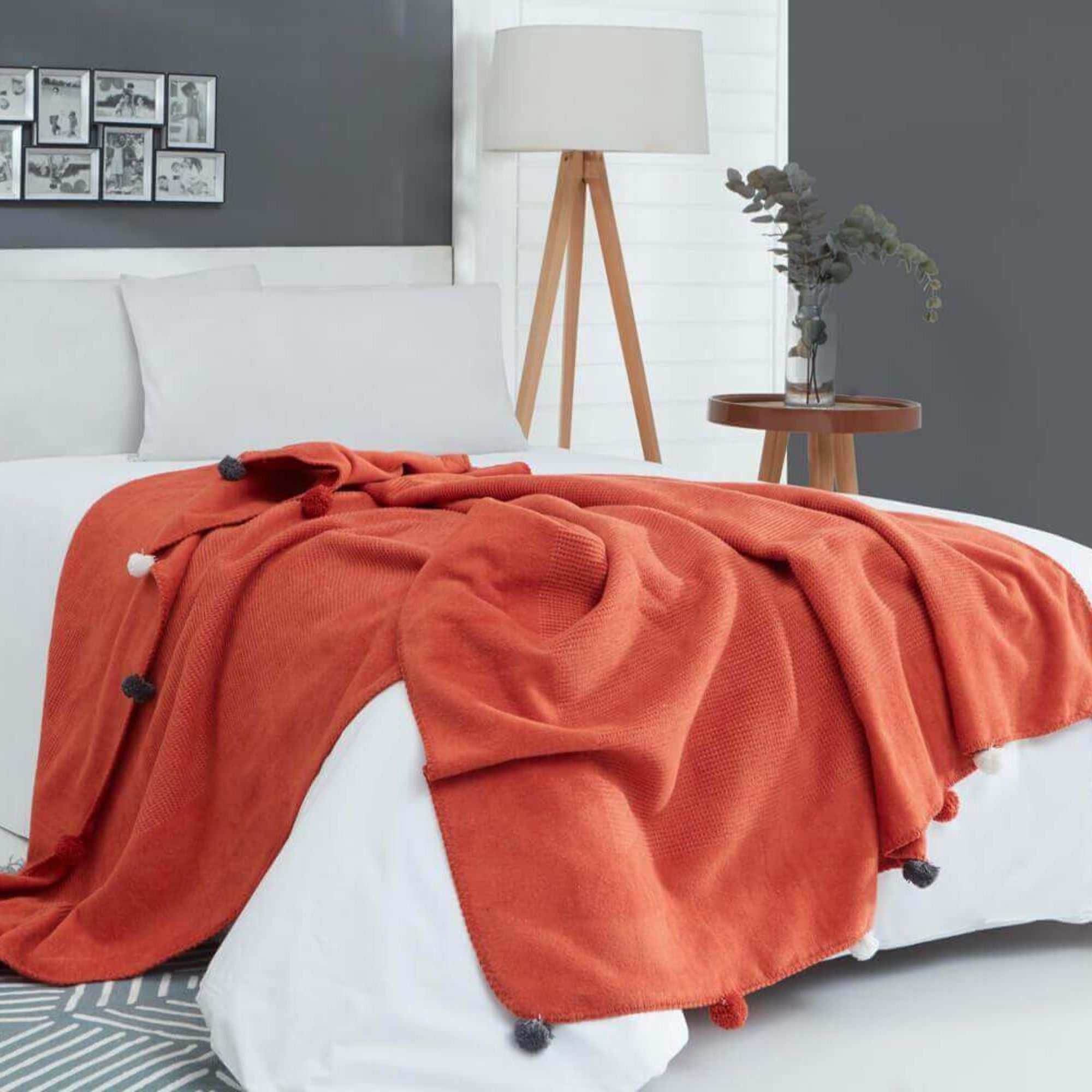 Lifestyle view of tile red pompom blanket on bed, stylish warm winter blanket for modern home interiors.