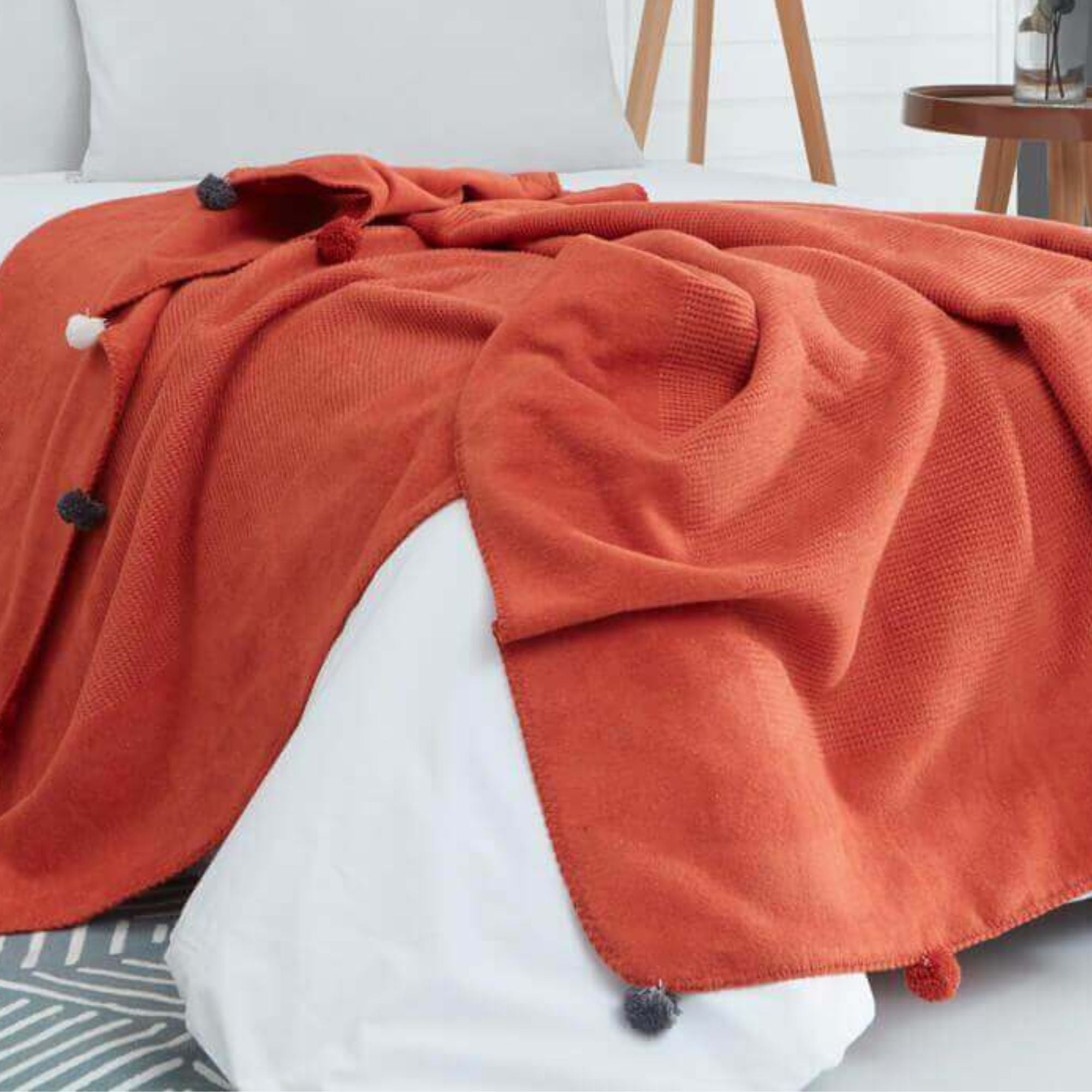 Close-up of tile red pompom throw blanket, soft fluffy texture, festive Christmas and New Year gift idea.
