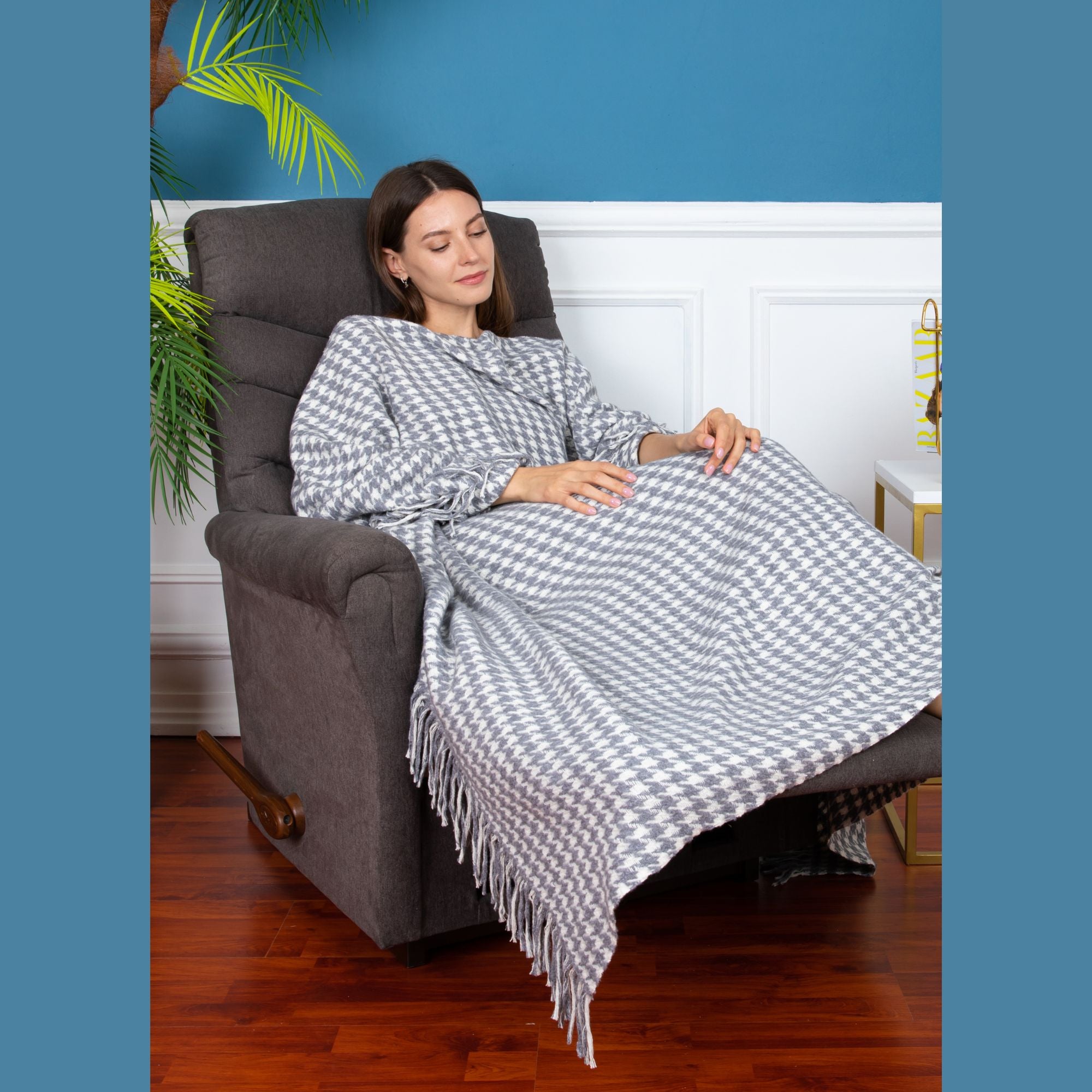 Trimita | Relaxed girl sitting on a sofa, enveloped in the Grey Houndstooth Luxury Throw Blanket, portraying its softness and warmth