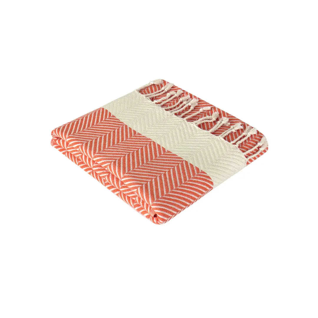 Opgevouwen oranje Hiera hamamdoek met crèmekleurig visgraatpatroon en franjes