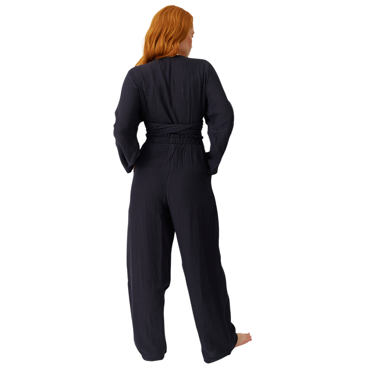 Full-length rear view on a white background showing the clean, flowy layout and relaxed silhouette of the black cotton muslin high-waisted trousers and long-sleeve wrap top.