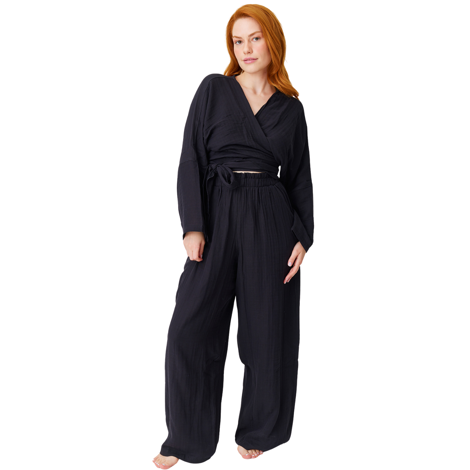 Full-length front shot of a barefoot model posing in a black casual muslin two-piece set, highlighting the loose wide-leg fit and breathable, lightweight summer drapes.