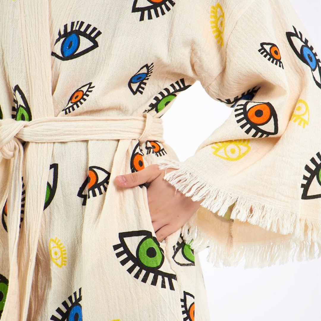 Close-up view of a kimono-style robe with colorful eye patterns, focusing on the belt tied at the waist and a pocket on the side