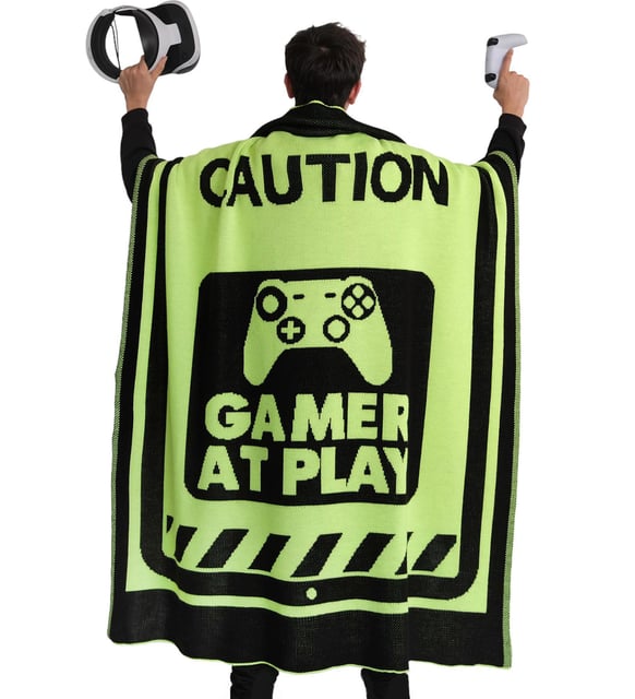 Person wearing Trimita  gemer blanket green cape with 'Caution: Gamer at Play' text and gaming controller graphic