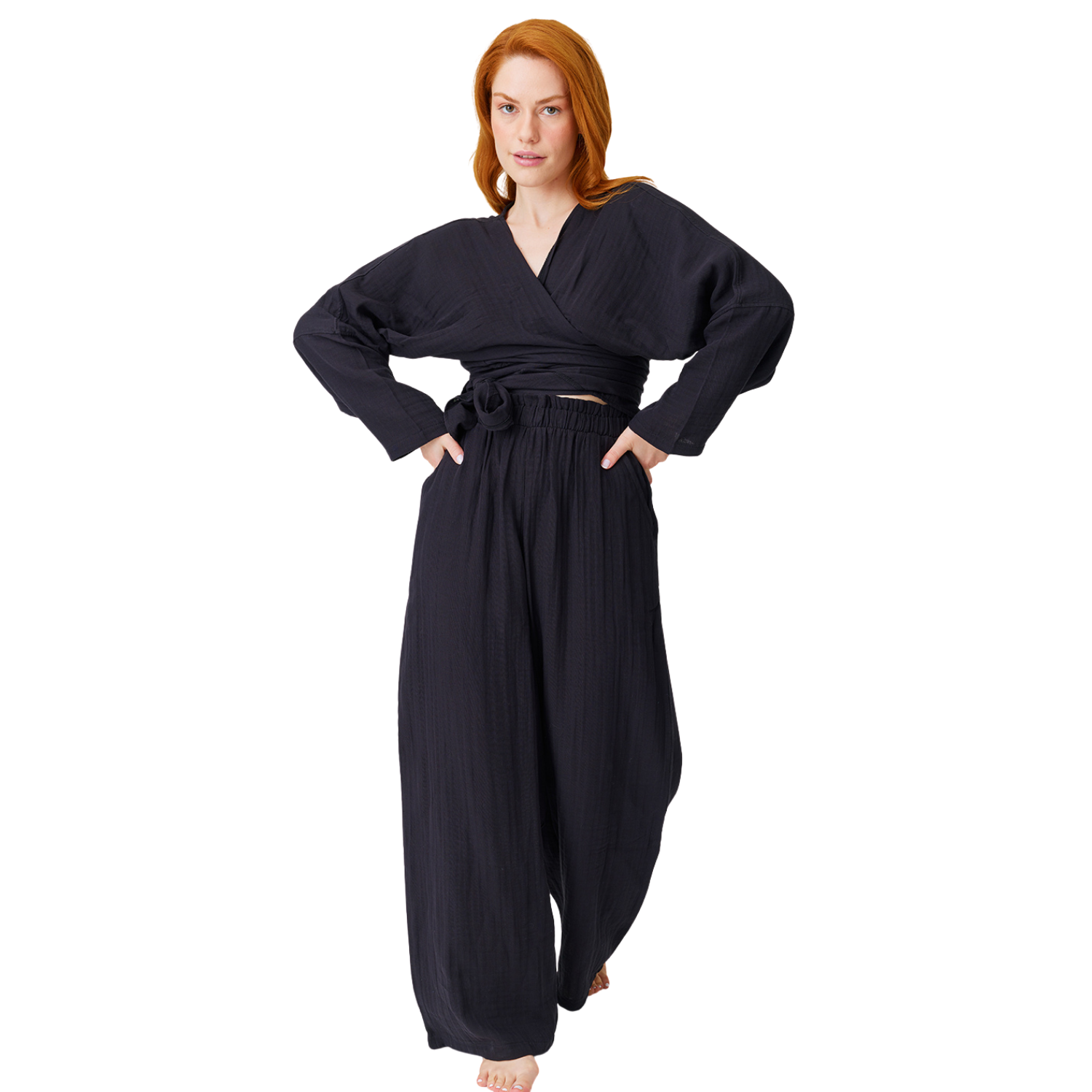 Full-length front shot of a barefoot redheaded model posing in a black casual muslin two-piece crop top set, highlighting the loose wide-leg fit and lightweight summer drapes.