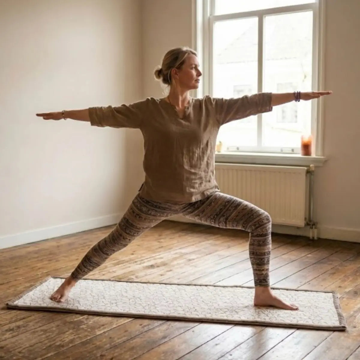 Woman practicing yoga in a room with wooden floor and large window
