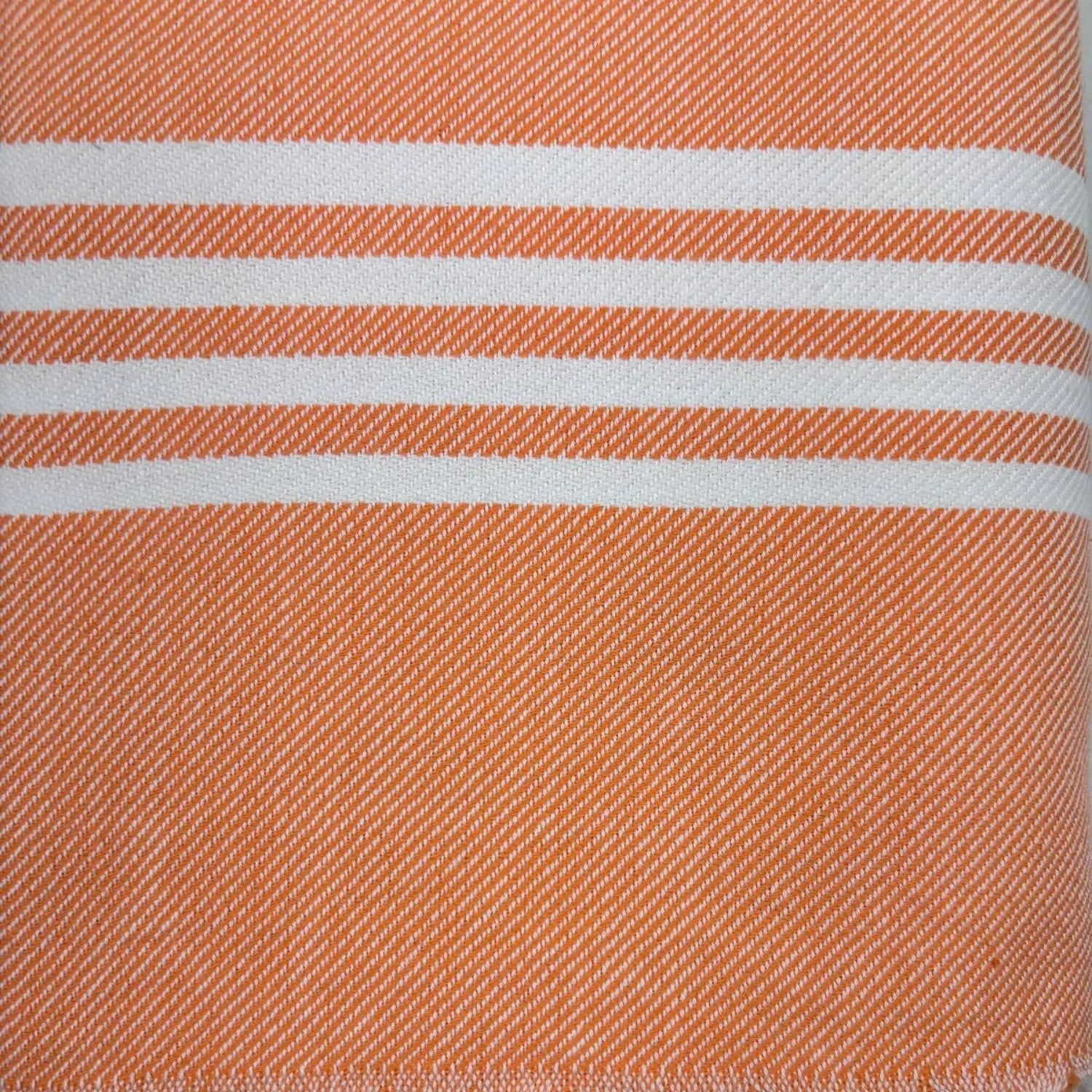 Folded orange Turkish towel with classic white stripes and hand-tied fringes.