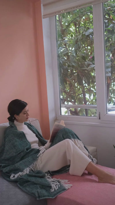 Girl reading a book in bed with Trimita lux throw blanket on her head.