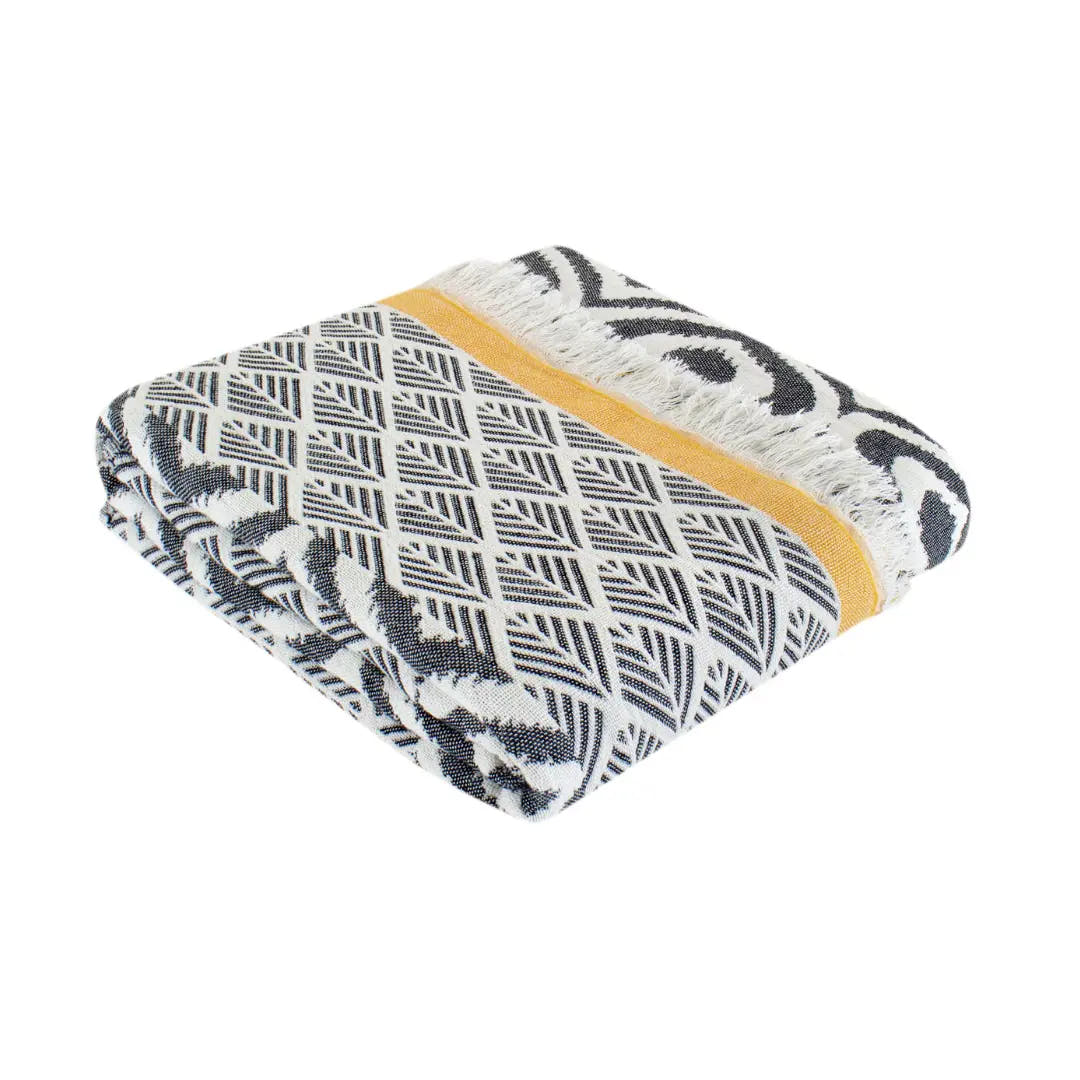 Trimita Asude plaid, opgevouwen met zwart-wit geometrisch patroon en gele streep