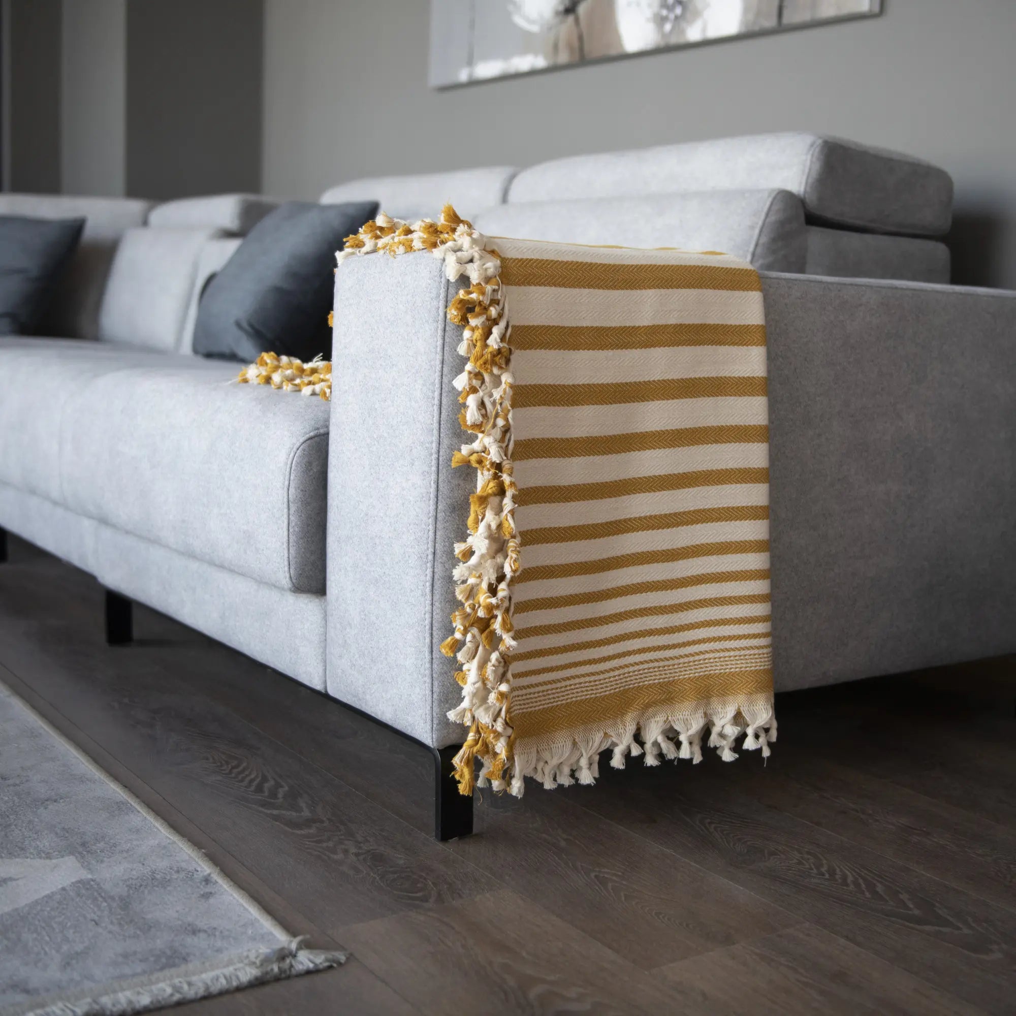 Trimita Sevda Bedspread in mustard stripes, folded on a sofa