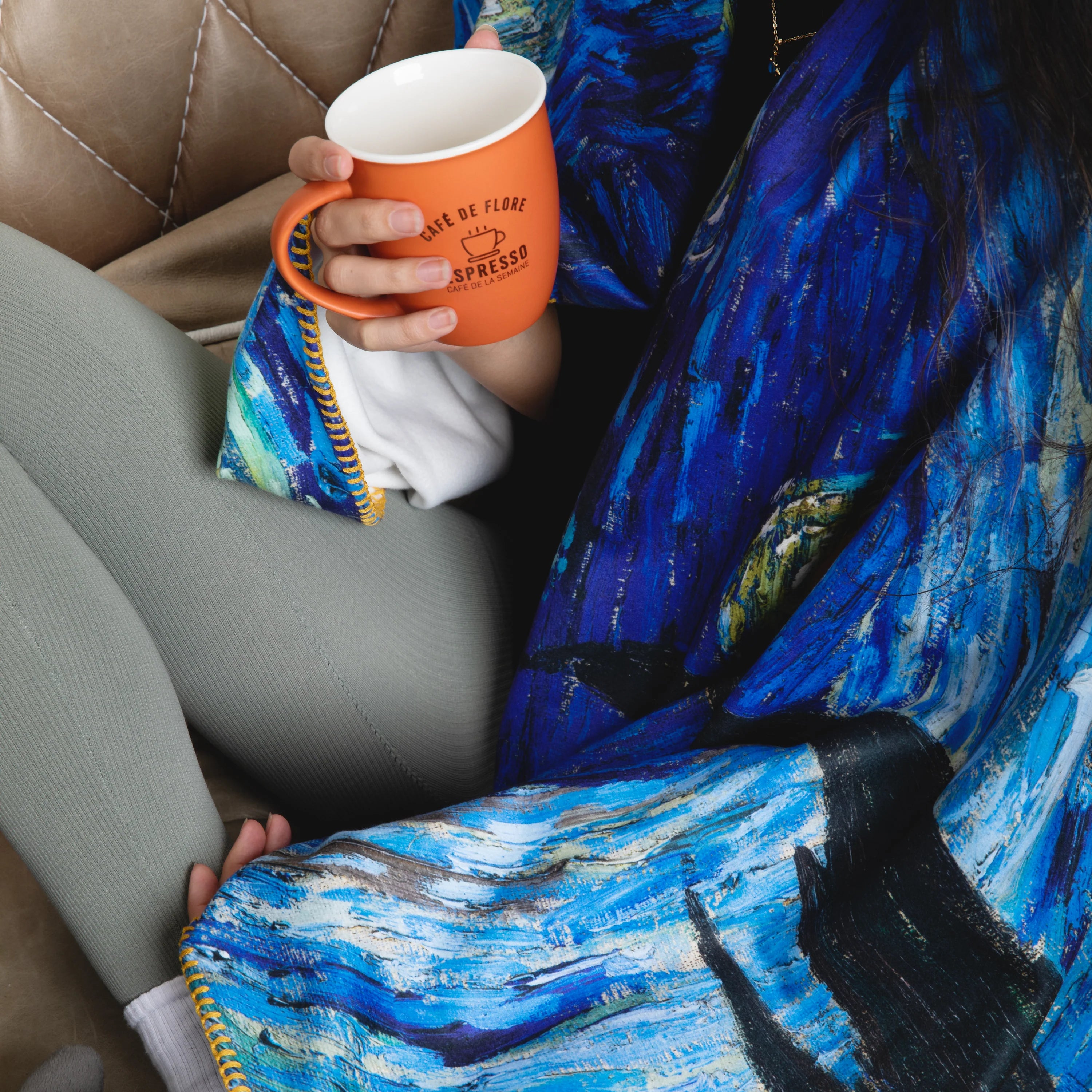 A woman drinks coffee while covered in Van Gogh's iconic Starry Night blanket.