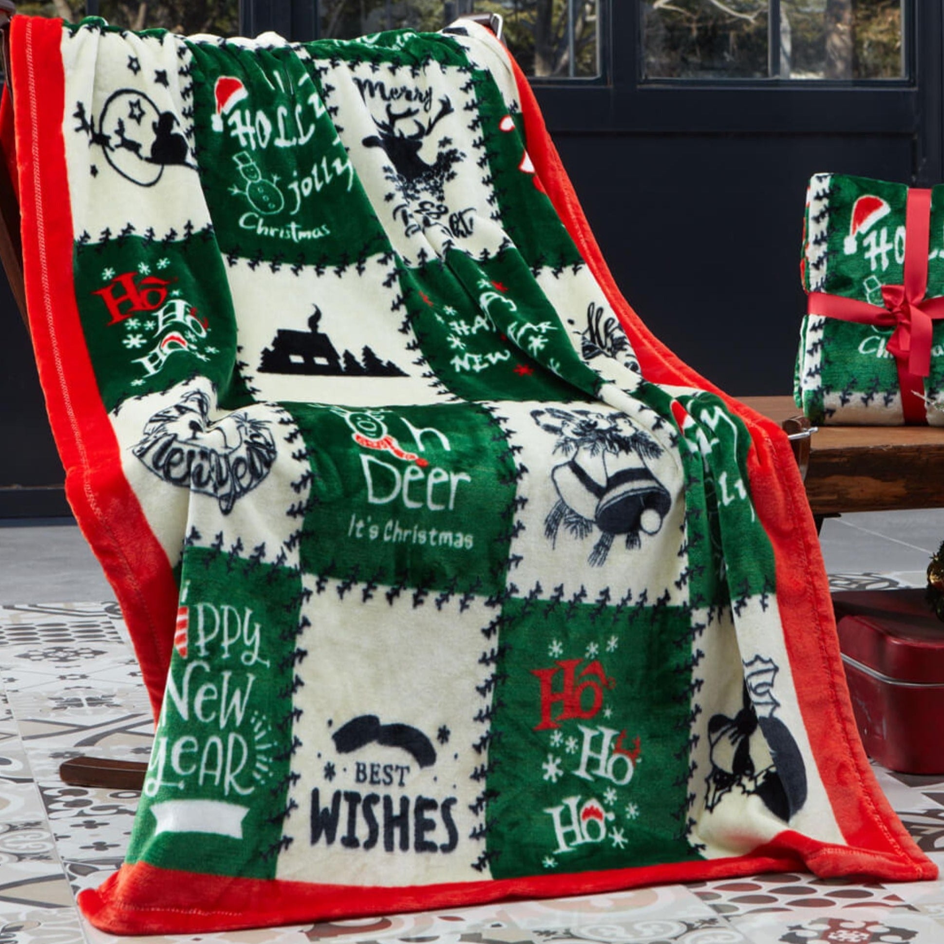 A green Christmas blanket with a deer design is on the couch.